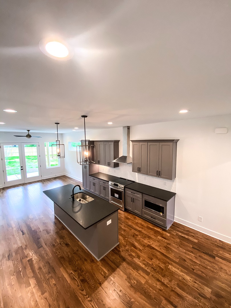 An unfinished open plan kitchen with grey cabinetry and a dark island, ready for site evaluation